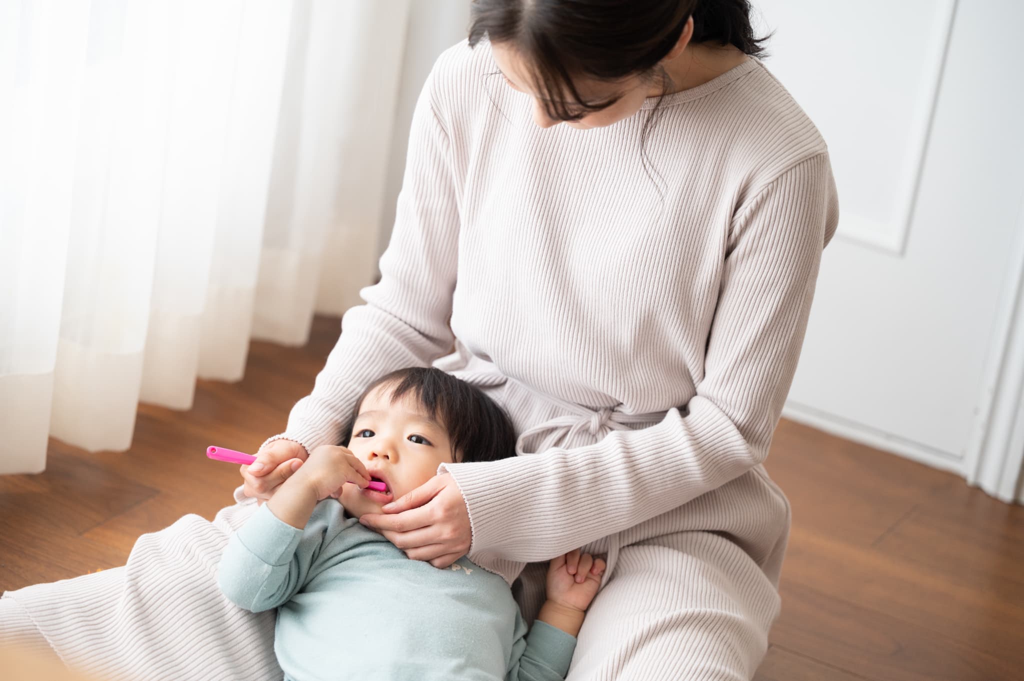 母親に歯を磨いてもらう小さい男の子