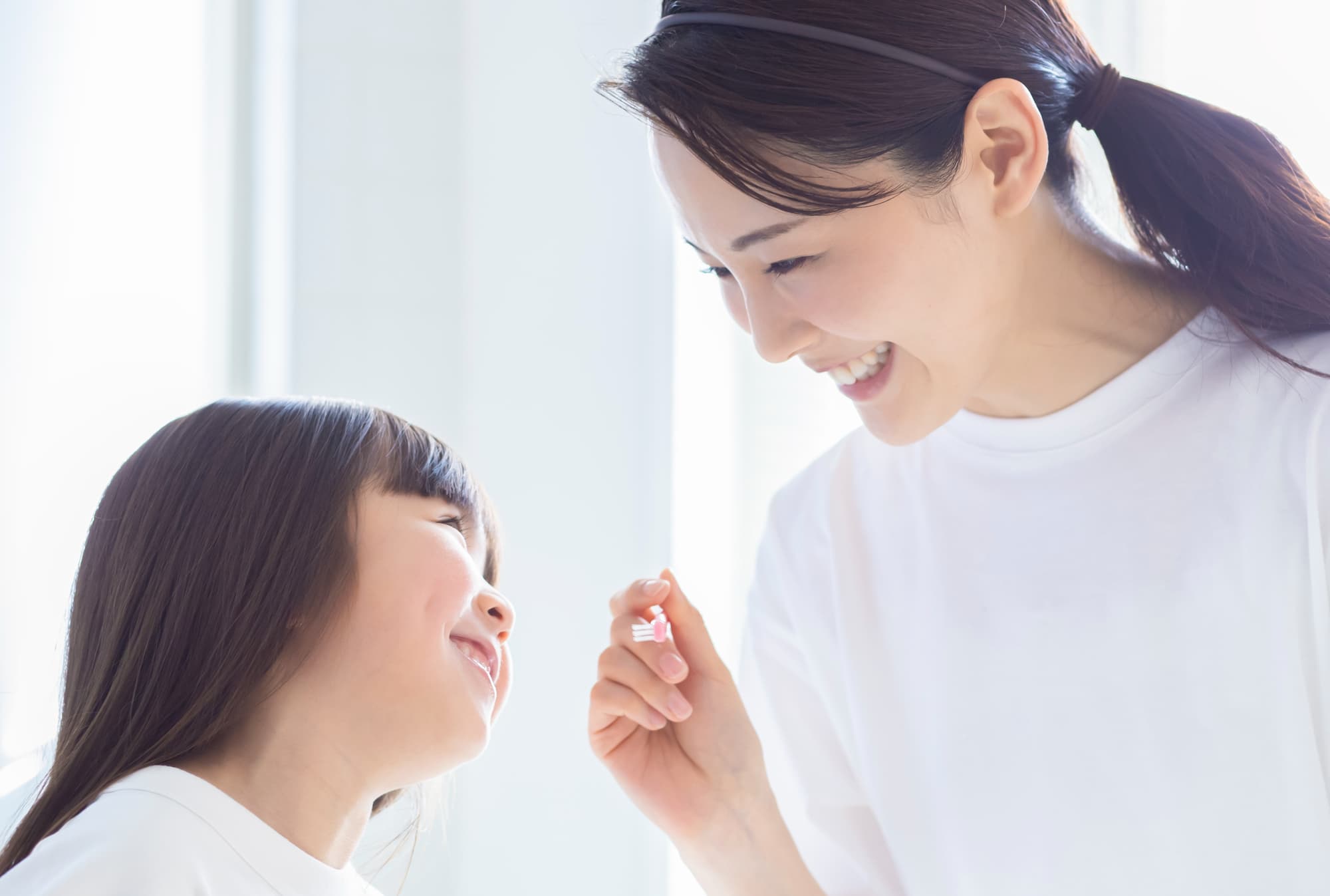 楽しんで歯磨きをする女の子と笑顔の母親