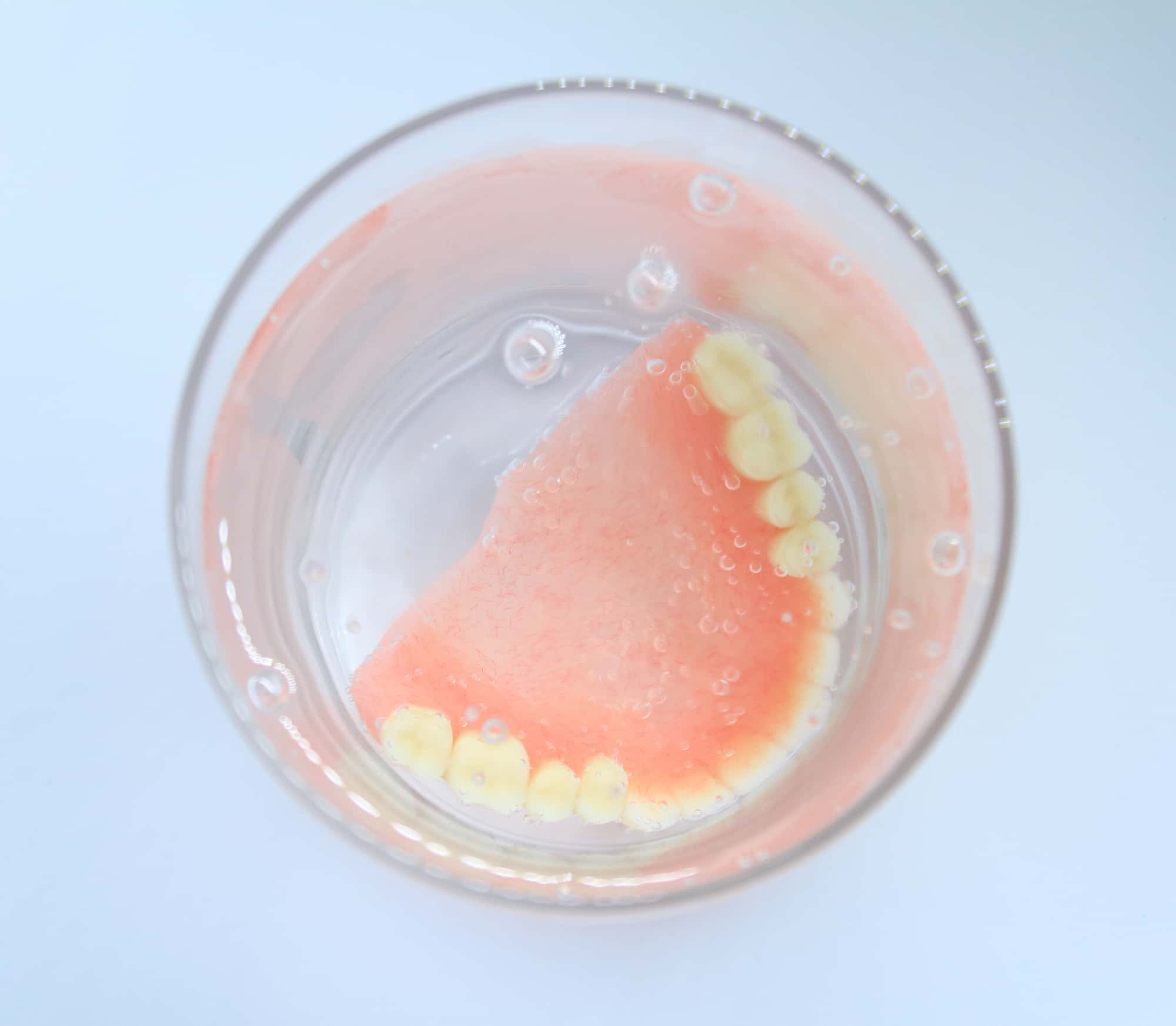 入れ歯を洗浄液に浸しているイメージ