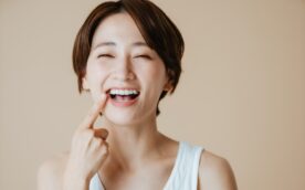 セラミック治療できれいになった歯を指さし笑顔の女性