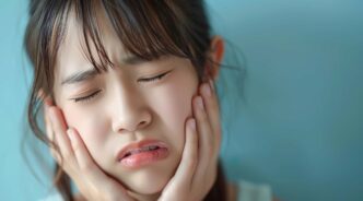 顎関節症の痛みで頬をおさえる女性
